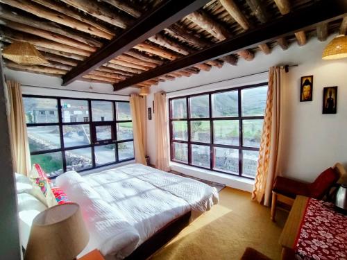 a bedroom with a bed and large windows at The Nomad's Cottage-Losar , nearest hotel stay to visit Chandra Tal - Lake , in Spiti Valley in Losar