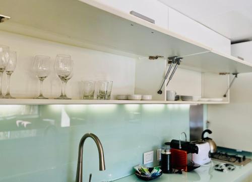 a kitchen with glasses on a shelf above a sink at La Sofia Apart & Wines in Mendoza