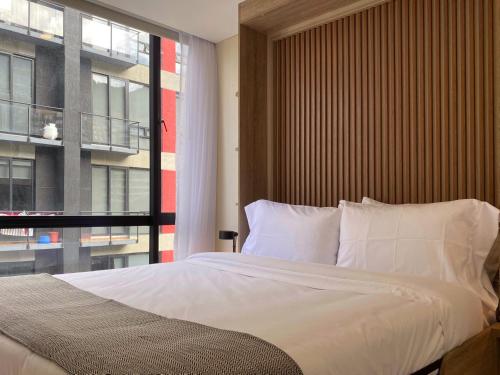 a bedroom with a large bed with a large window at Nuo by Wynwood House in Bogotá