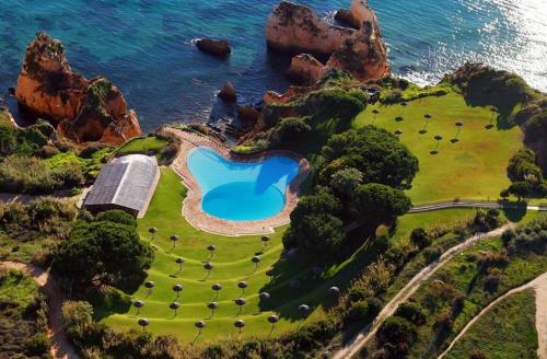 an island with a swimming pool on the ocean at Prainha-Inn in Alvor
