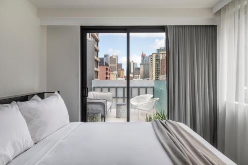 メルボルンにあるLancemore Crossley St. Melbourneのベッドルーム1室(ベッド1台付)が備わります。バルコニーの景色を望めます。