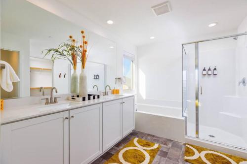 a white bathroom with a sink and a shower at 7BR Pickleball Firepit Outdoor Kitchen Game Room in Coachella