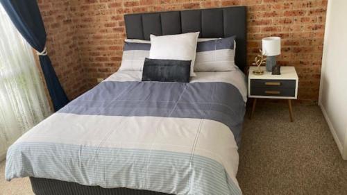 a bedroom with a large bed with a brick wall at The Olive - Family & Pet Friendly in Sanctuary Point
