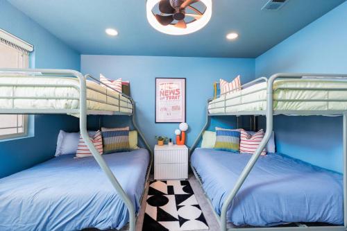 two bunk beds in a room with blue walls at 7BR Pickleball Firepit Outdoor Kitchen Game Room in Coachella