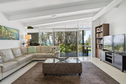 a living room with a couch and a tv at Sabia Beach House 2.0 - Beachfront - Sleeps 6 in Vincentia