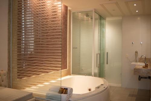 a bathroom with a tub and a glass shower at Hotel Villa Reggia in Rio de Janeiro