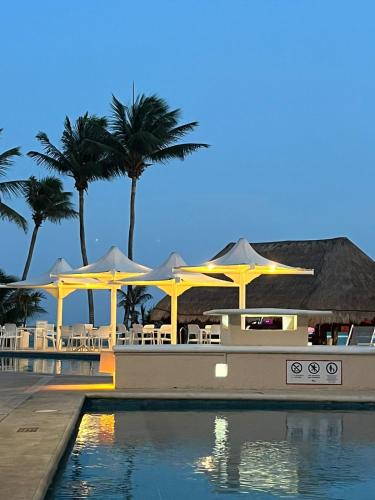 a resort with tables and umbrellas and a swimming pool at Spacious and comfortable apartment w pool and golf in Tulum