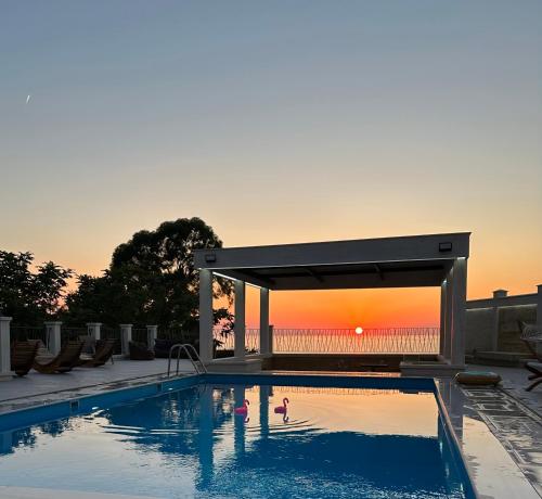 a swimming pool with a sunset in the background at Villa Sunlight in Gonio