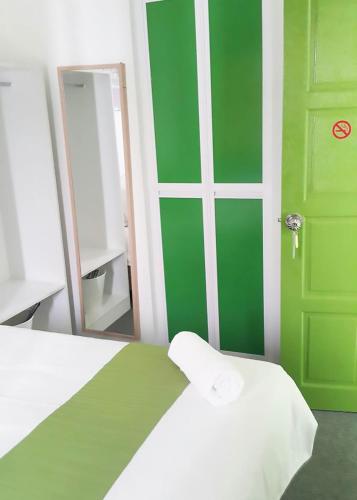 a bedroom with a green door and a mirror at Olive Hotel in Johor Bahru
