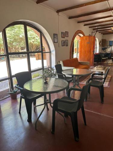 two tables and chairs in a room with windows at CaminAndes Hostal in San Pedro de Atacama