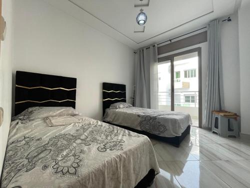 a bedroom with two beds and a window at Residence Rimal 5 Martil in Tétouan