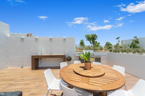 a wooden table and white chairs on a patio at New Penthouse in Medano with Jacuzzi and Terrace in Cabo San Lucas