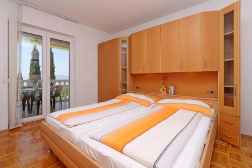 a bedroom with a large bed with wooden cabinets at Apartments with parking space Kostrena, Rijeka - 23422 in Kostrena