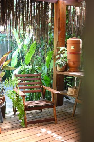 a wooden chair sitting on a porch with plants at Pousada Habitat Caraíva in Caraíva