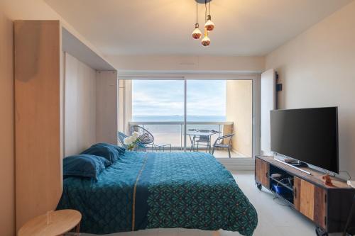 une chambre avec un lit et une télévision à écran plat dans l'établissement L'Océan à Vos Pieds Appartement Vue Panoramique La Baule, à La Baule