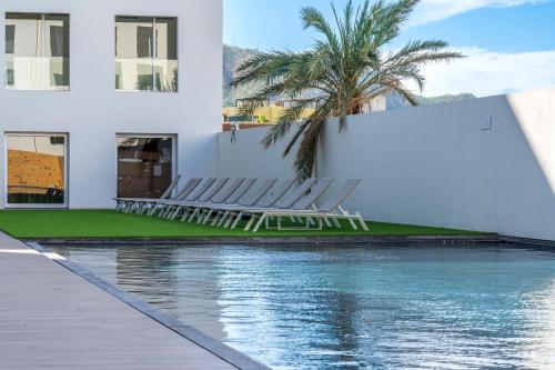 a pool with chairs next to a building at New Penthouse in Medano with Jacuzzi and Terrace in Cabo San Lucas