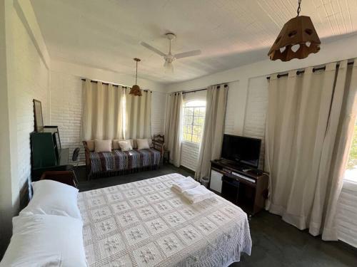 a bedroom with a bed and a couch and a television at Recanto do Coração in Itaúna