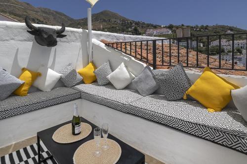 a bench with pillows and a table on a balcony at Casa Jardin Competa in Cómpeta
