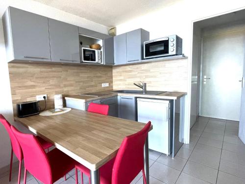 a kitchen with a wooden table and pink chairs at Studio-cabine à Banyuls-sur-Mer climatisé, terrasse, parking, Wi-Fi - FR-1-309-210 in Banyuls-sur-Mer