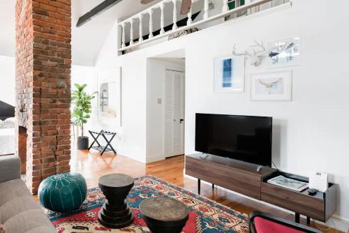 a living room with a large television and a brick wall at Chic Spot near the Lower French Quarter in New Orleans