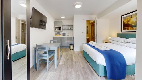 two beds in a room with a table and a kitchen at Bicester Court in Bicester