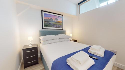a bedroom with a bed with white sheets and towels at Bicester Court in Bicester