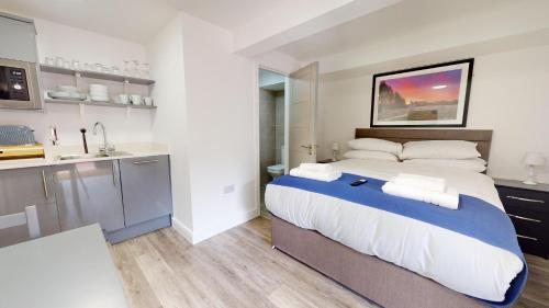 a bedroom with a large bed and a kitchen at Bicester Court in Bicester