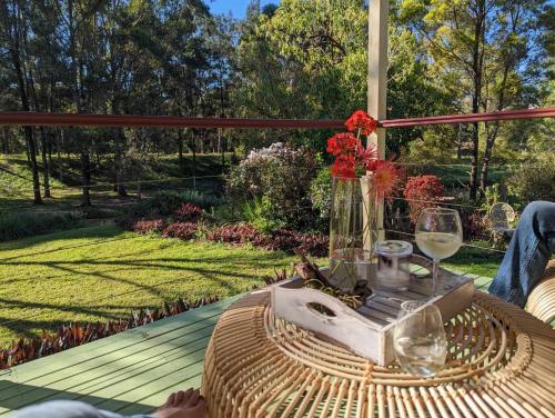 a table with a vase and glasses on a deck at Amamoor - Living Waters in Amamoor