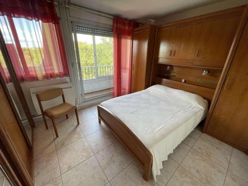 une chambre avec un lit, une chaise et une fenêtre dans l'établissement Appartement 3 Pièces, Piscine, Proche Plage, Wi-Fi, Garage - FR-1-328-269, à La Grande Motte
