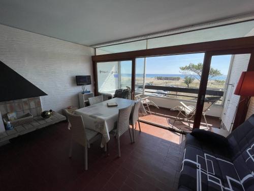 - un salon avec une table, des chaises et une grande fenêtre dans l'établissement Saint-Cyprien : T2 confortable en bord de mer avec parking et animaux admis - FR-1-106-106, à Saint-Cyprien