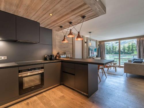 une cuisine avec un comptoir noir et un salon dans l'établissement Appartement chaleureux 4 pers, Courchevel Centre, à 2 pas des pistes, parking, SPA inclus - FR-1-631-204, à Courchevel