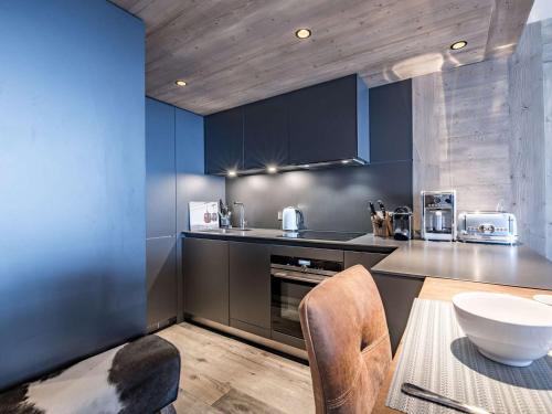 une cuisine avec des placards bleus et une table avec des chaises dans l'établissement Appartement 76m², 6-7 pers, Courchevel Village, pied des pistes, centre, balcon, spa, parking, Wi-Fi. - FR-1-631-202, à Courchevel