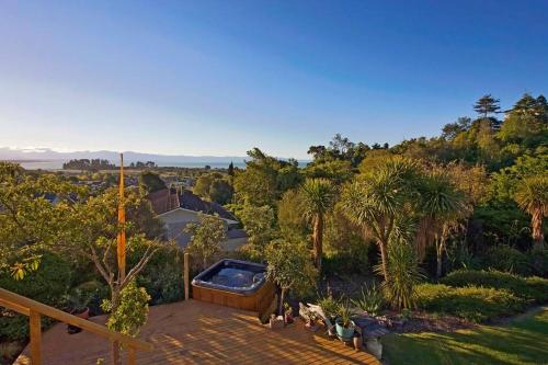a hot tub on a patio with palm trees at Tahuna Views - Spa Pool, Sea Views, Great for Kids in Nelson
