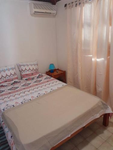 a small bedroom with a bed with a window at Madinina beach in Sainte-Anne