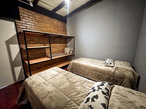 a bedroom with two beds and a brick wall at Casa Céntrica Ideal Familias Estacionamiento para 3 vehículos Ubicación Premium in La Cieneguita