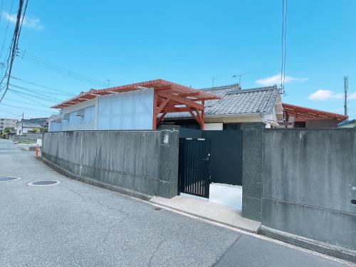 a fence in front of a house on a street at 淡路島一望 海まで1分 本格檜サウナのある古民家 10人まで定額料金 in Akashi