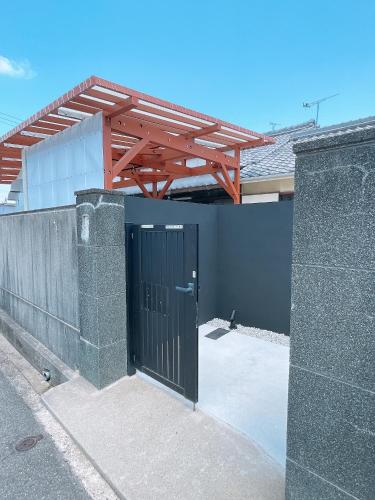 a building with a black door and a wooden roof at 淡路島一望 海まで1分 本格檜サウナのある古民家 10人まで定額料金 in Akashi