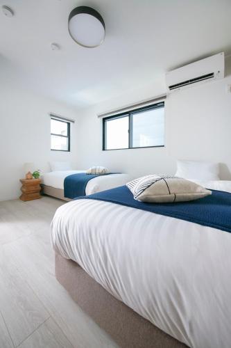 two beds in a bedroom with two windows at pufuka Higashi Mukojima 4 in Tokyo