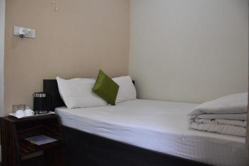 a bed with white sheets and a green pillow at Rolyda Guest House in Shillong