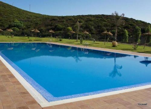 a large blue swimming pool with a hill in the background at Grand Luxury Apartment Furnished in Tetouan
