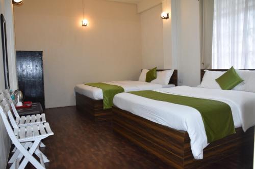 a hotel room with two beds and a chair at Rolyda Guest House in Shillong