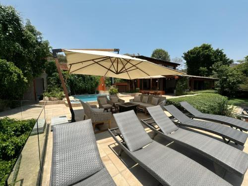 a group of chairs and an umbrella next to a pool at Casa el mirador-Valle de Bravo in Colorines