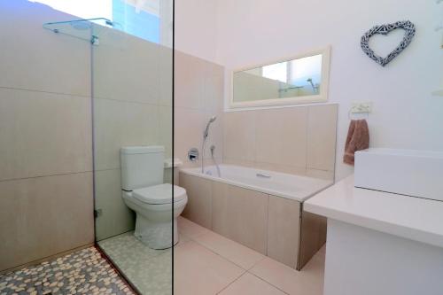 a bathroom with a toilet and a tub and a sink at Arniston Holiday Cottage in Arniston