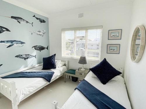 Un dormitorio con dos camas y una ventana. en Oorgenoeg In Arniston, en Arniston