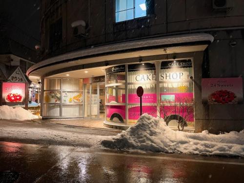 a cake shop with a pile of snow in front of it at HOTEL 24sweets HAKUBA in Hakuba