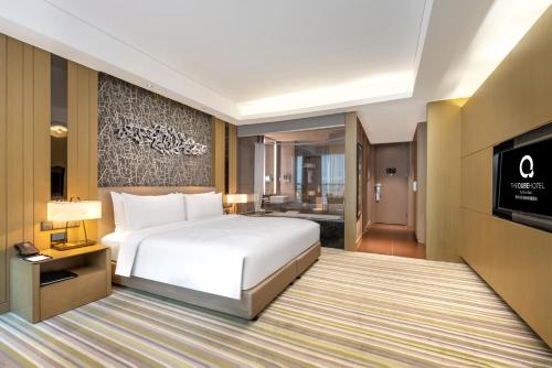 une chambre d'hôtel avec un lit et une télévision à écran plat dans l'établissement The Qube Xuzhou, à Xuzhou