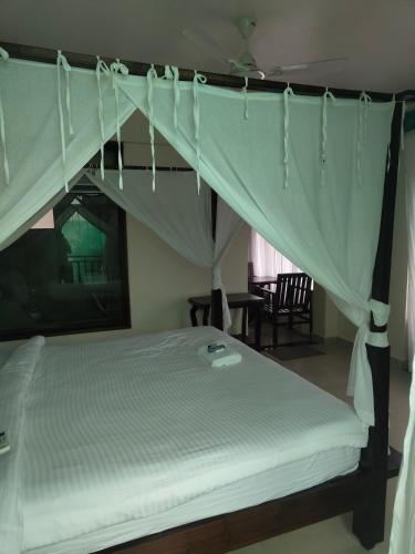 a bedroom with a canopy bed with white sheets at Shivam bnb Boutique Apartments in Mandrem