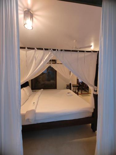 a bedroom with a canopy bed with white curtains at Shivam bnb Boutique Apartments in Mandrem