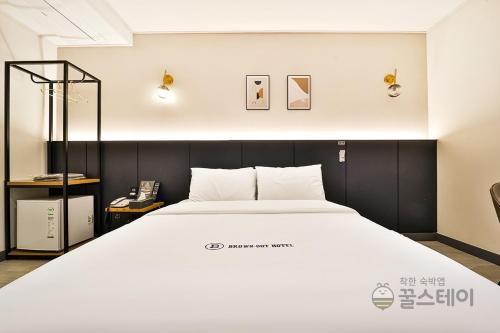 a large white bed in a room with a phone at Brown Dot Hotel Guun in Suwon