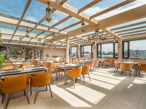 a dining room with tables and chairs and windows at Eternity By Greenscape in Srinagar
